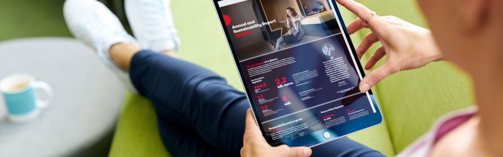 EOS ASR: Slika prikazuje mladu ženu koja drži tablet i na njemu gleda EOS-ovo Godišnje izvješće o održivosti.