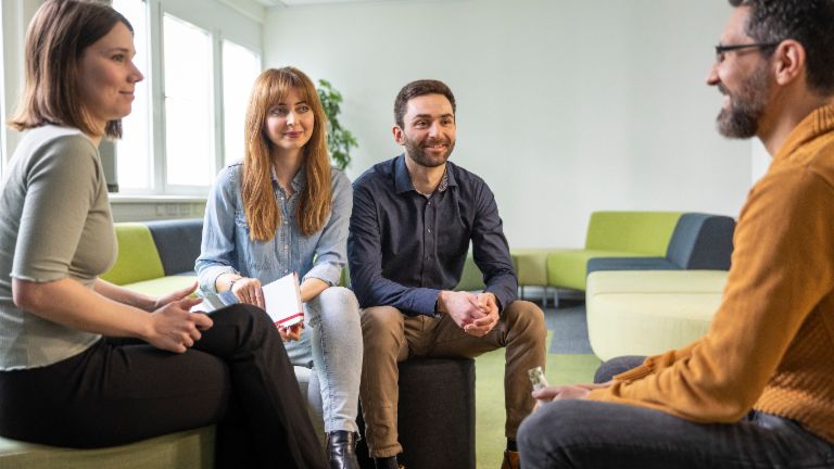 Group of four EOS colleagues sitting in workshop area and discuss a topic