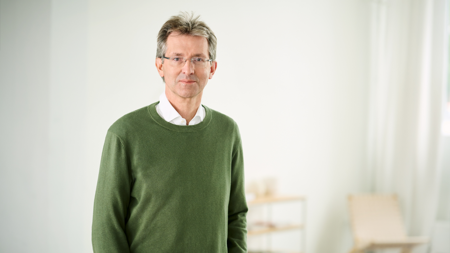 Justus Hecking-Veltman, financijski direktor, odjeven u zeleni džemper i bijelu košulju, stoji u svijetloj sobi.