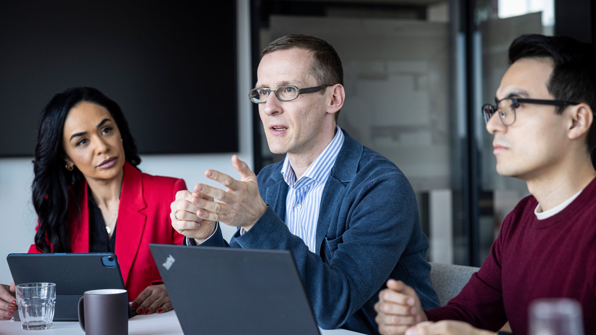 Tri osobe razgovaraju u uredu.