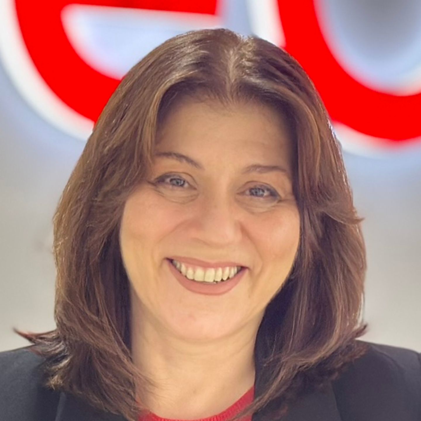 Belén Barreiro, agent kontaktnog centra u EOS-u u Španjolskoj, naslonjena je na pult u crnom sakou ispred svijetlog EOS-ovog logotipa.
