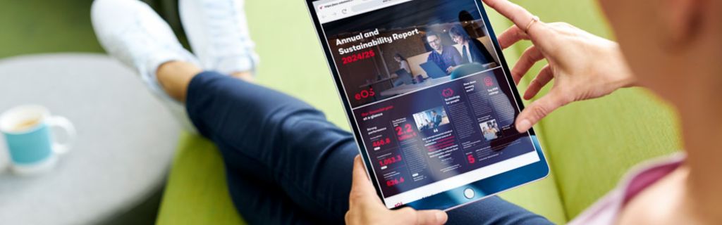 Osoba na zelenom kauču koja pregledava EOS Godišnje izvješće i Izvješće o održivosti 2024/25 na tabletu