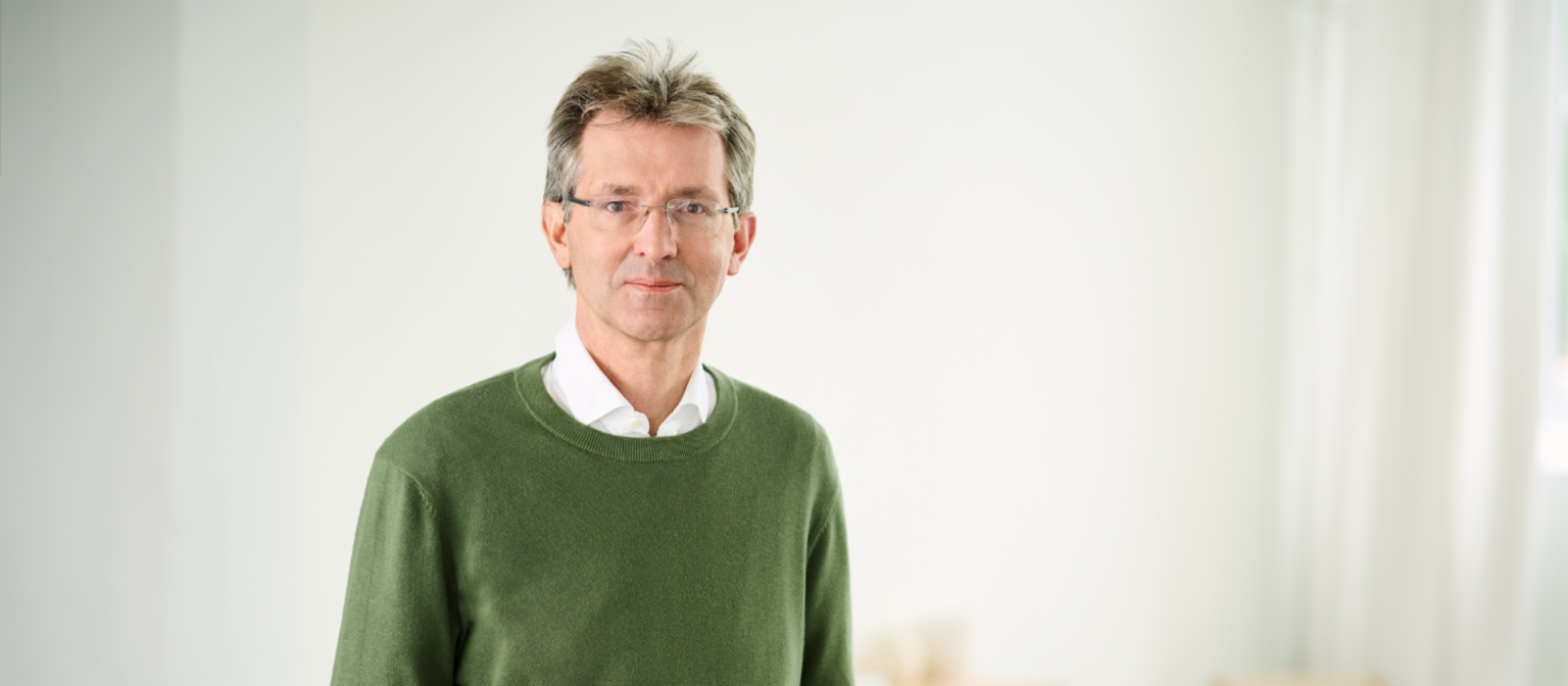Justus Hecking-Veltman, financijski direktor, odjeven u zeleni džemper i bijelu košulju, stoji u svijetloj sobi.