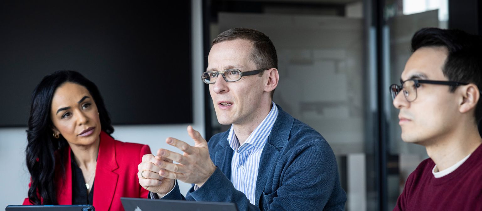 Tri osobe razgovaraju u uredu.