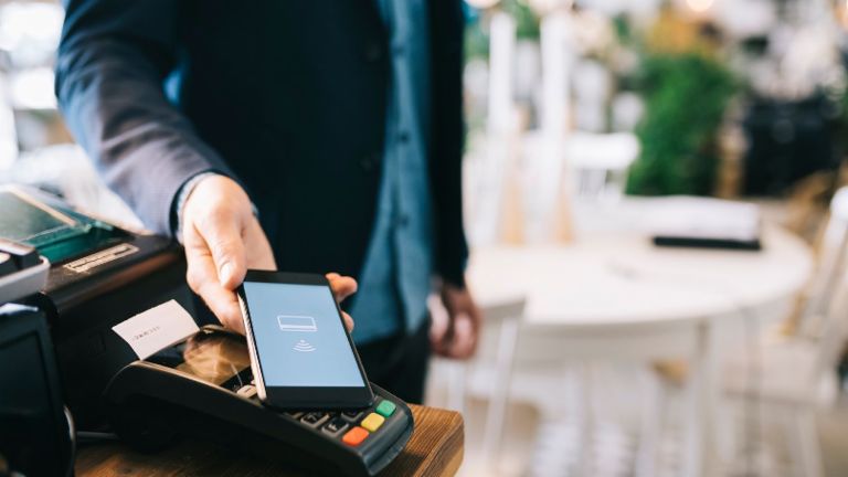 Digitalno plaćanje: Čovjek stavlja svoj mobilni telefon na platni terminal 